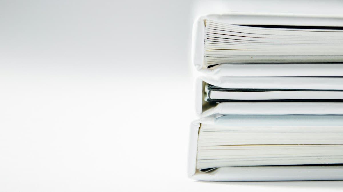 A stack of white binders on a clean surface